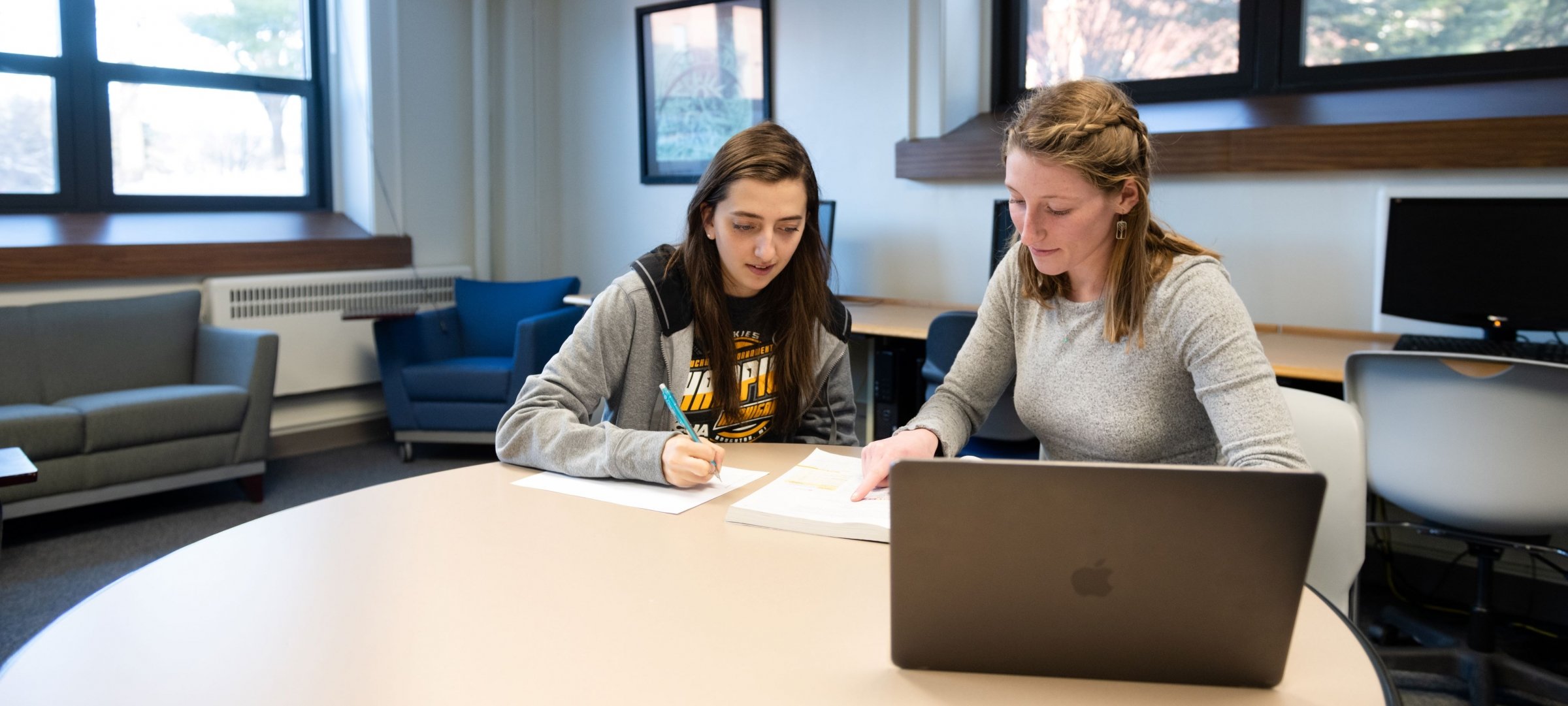 Students in a study space working on a laptop.