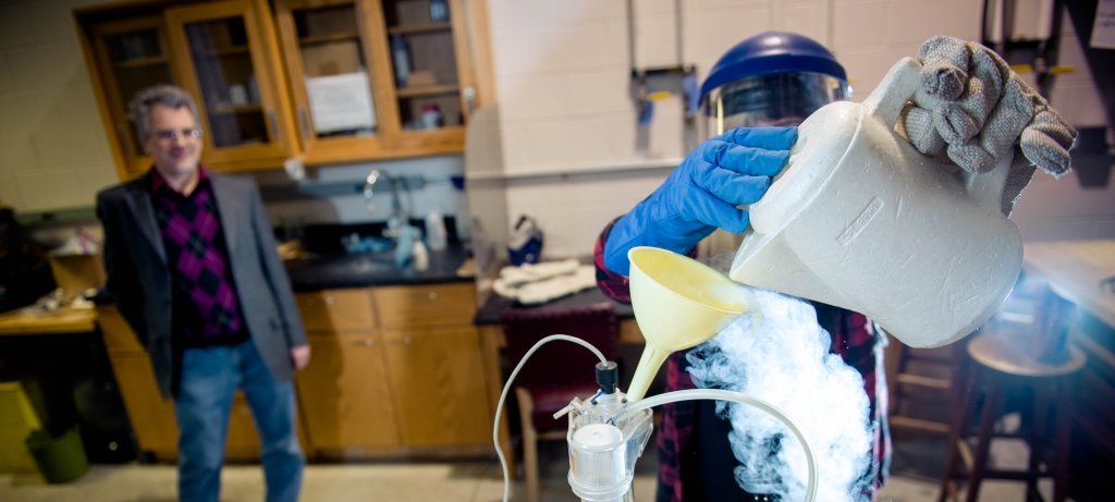 Person watching a researcher pour into a funnel.