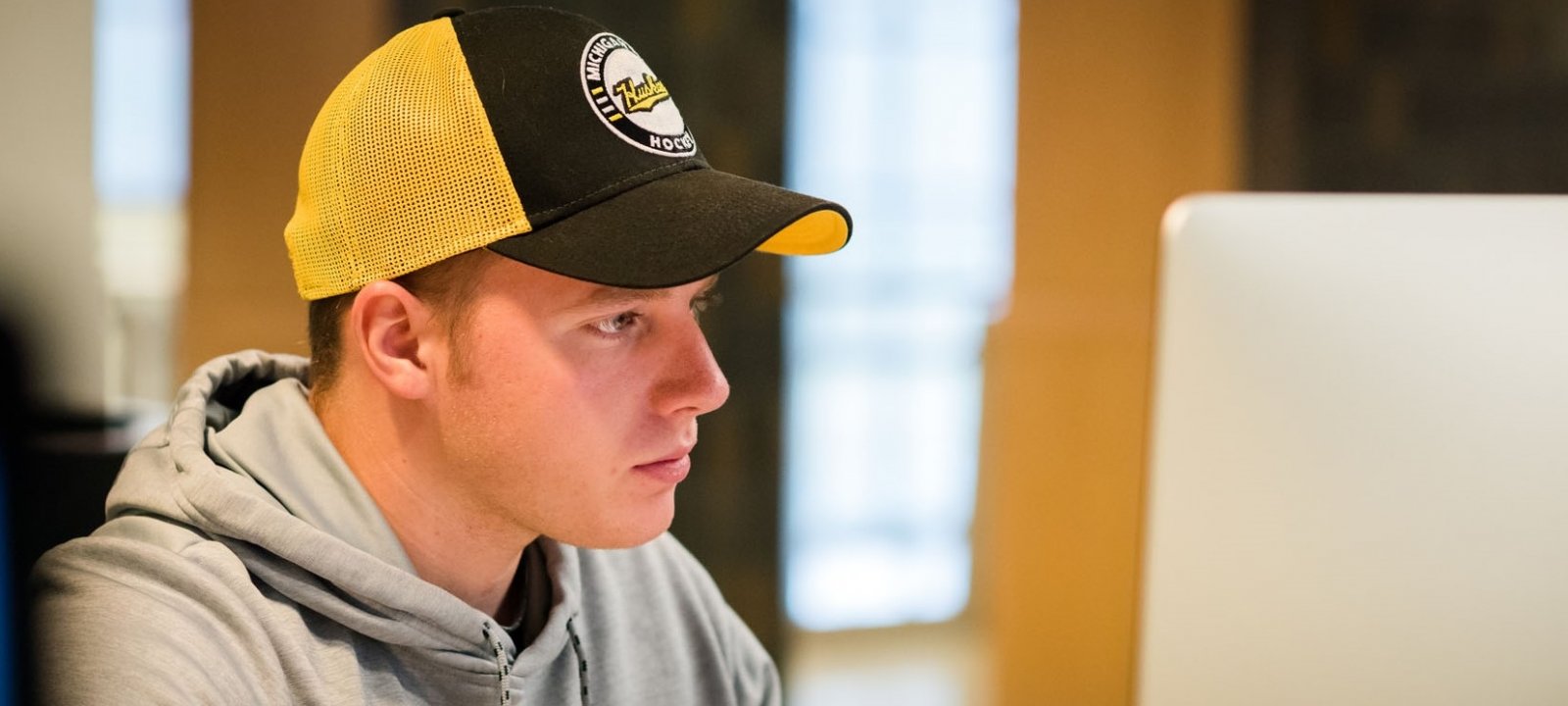 Young man in a huskies cap working on his online course.