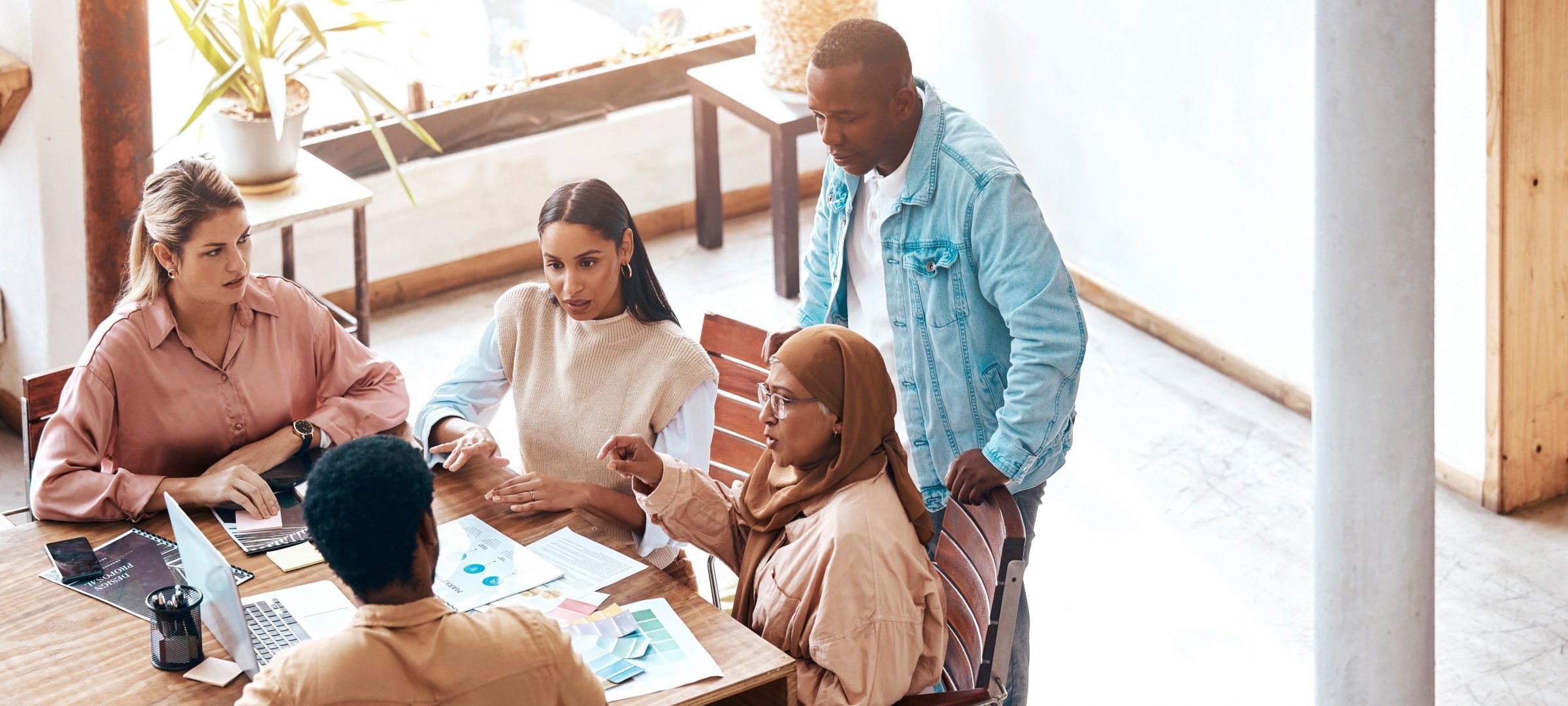 A group of business people talking and looking over a laptop.