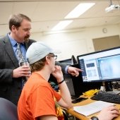 Faculty pointing at a student's computer screen.