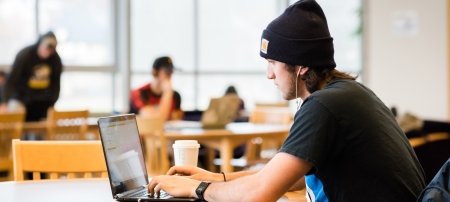 Student typing on a laptop in the Library.