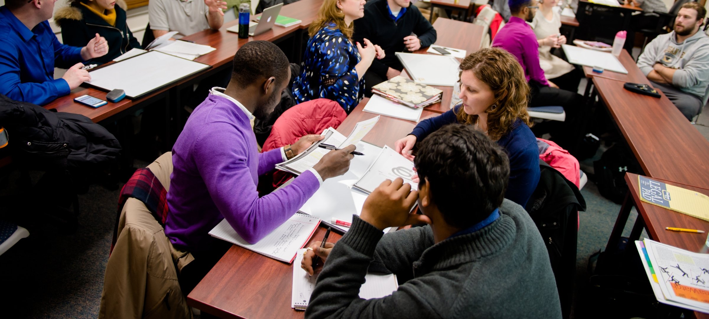 Business grad students in a class room meeting in groups.