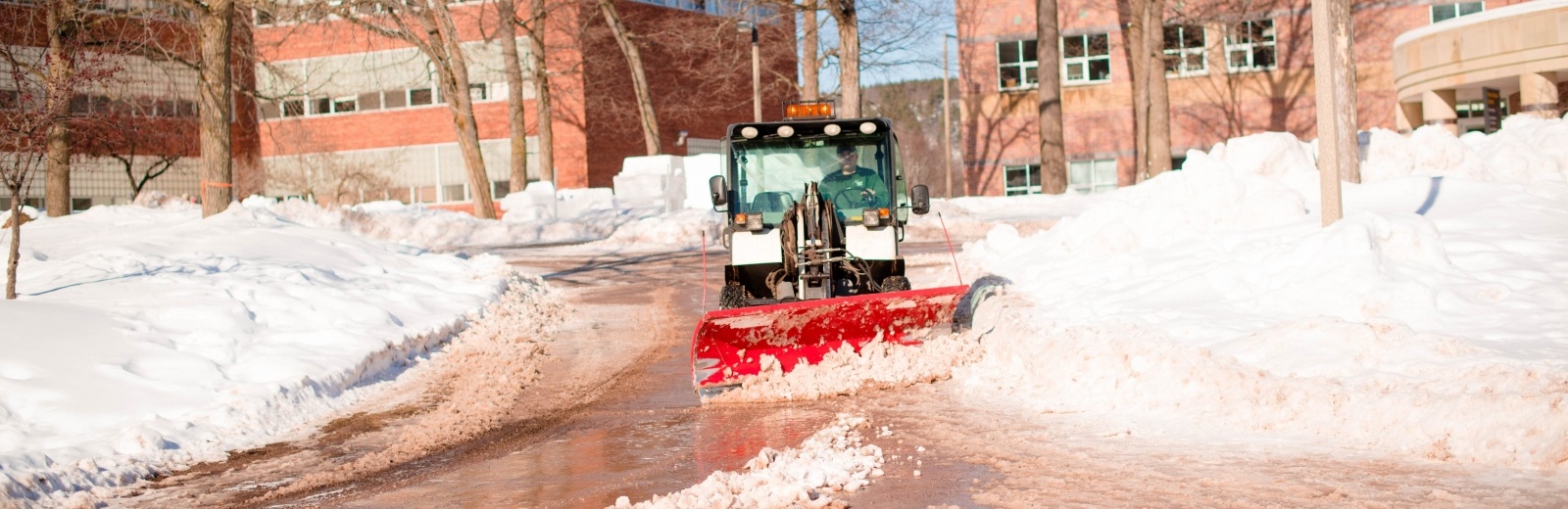 Plow clearing a sidewalk of snow.